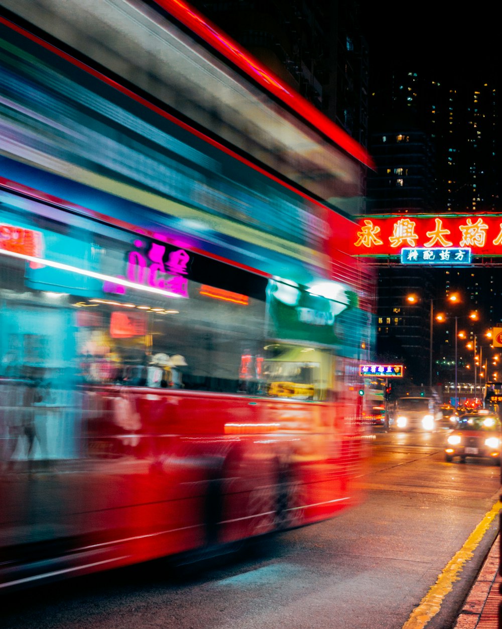 red and and blue double deck bus on roadway in time lapse photography