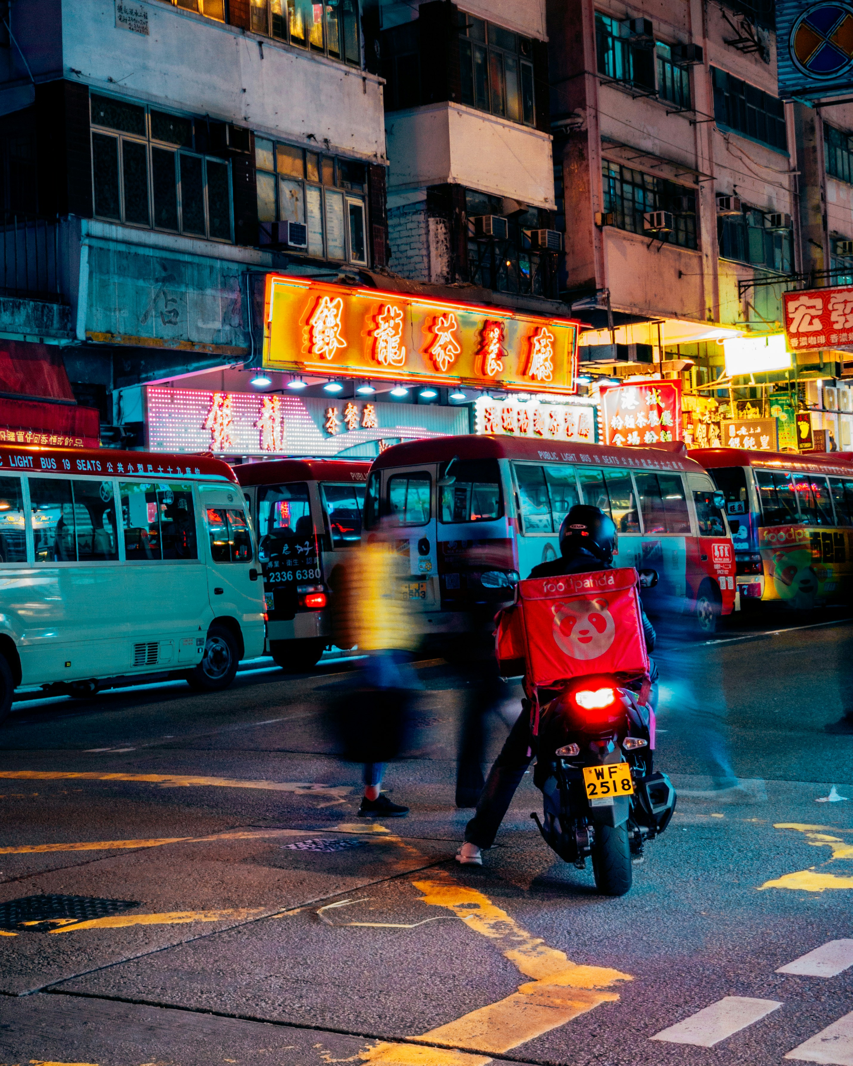Delivery rider on motorcycle with food bag, modern city street in background