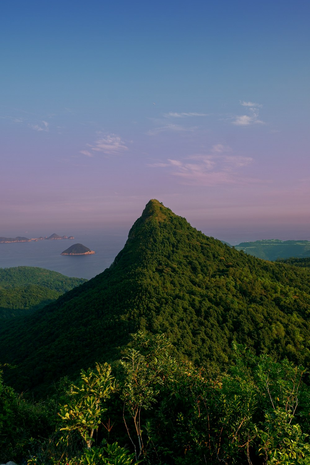 hill facing body of water under blue sky