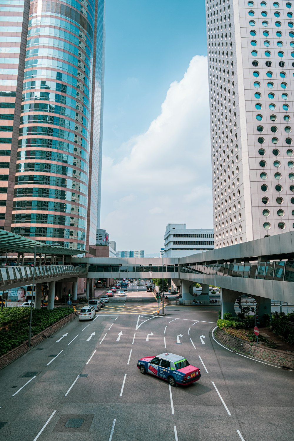 red and white sedan on road between high-rise buildings