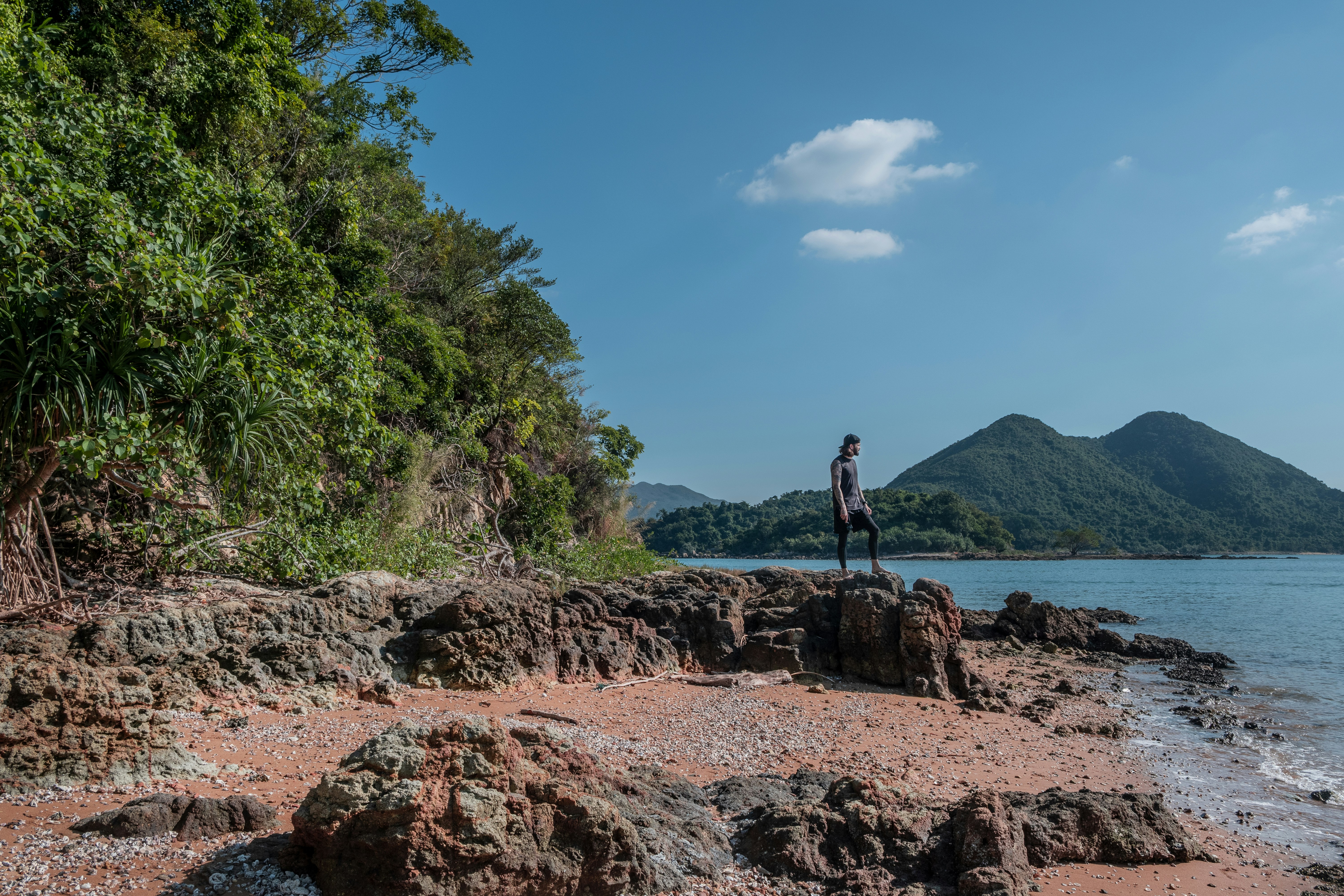 hombre lijando en la roca frente al océano bajo el cielo azul