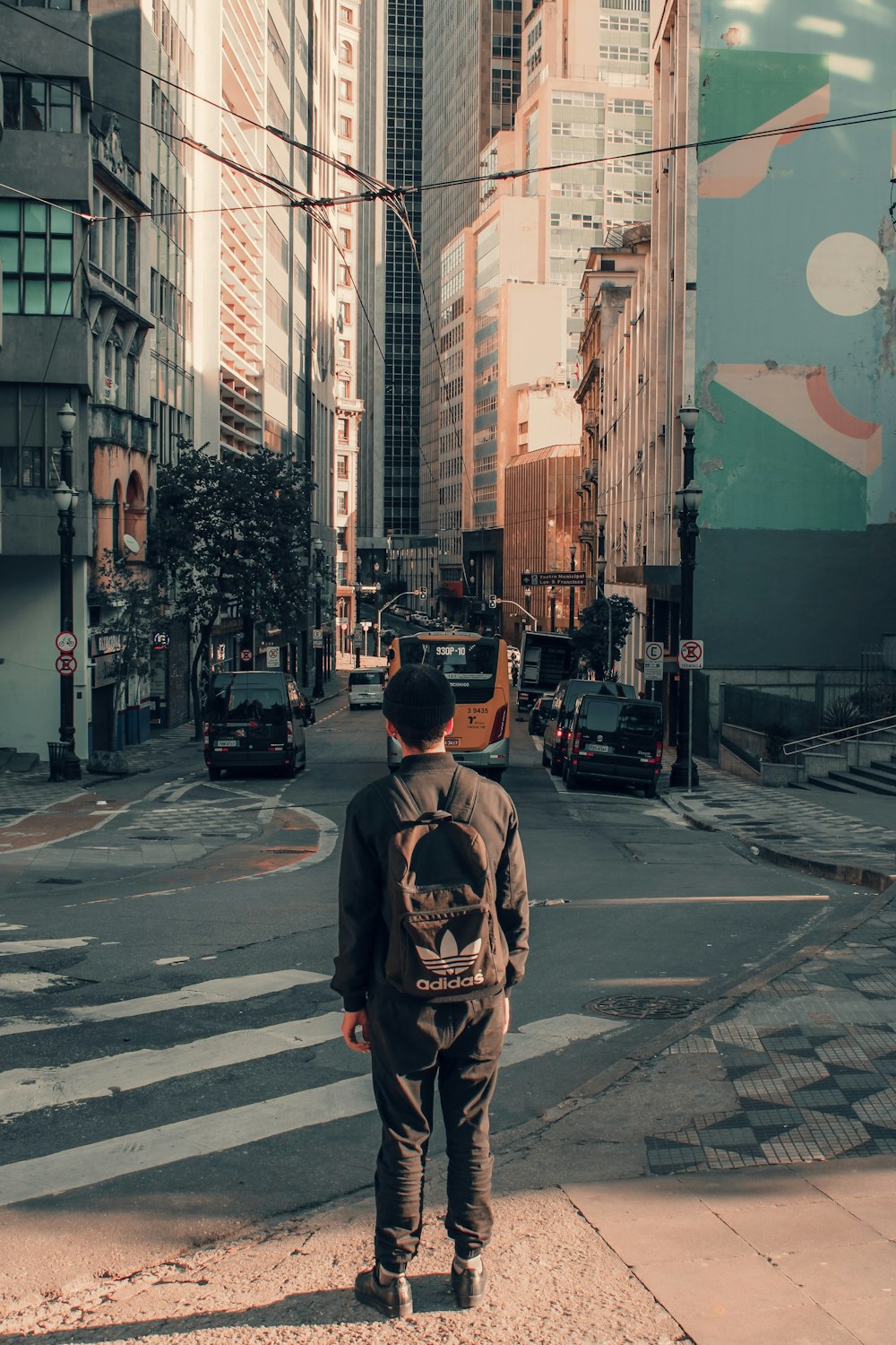 man carrying backpack standing on street
