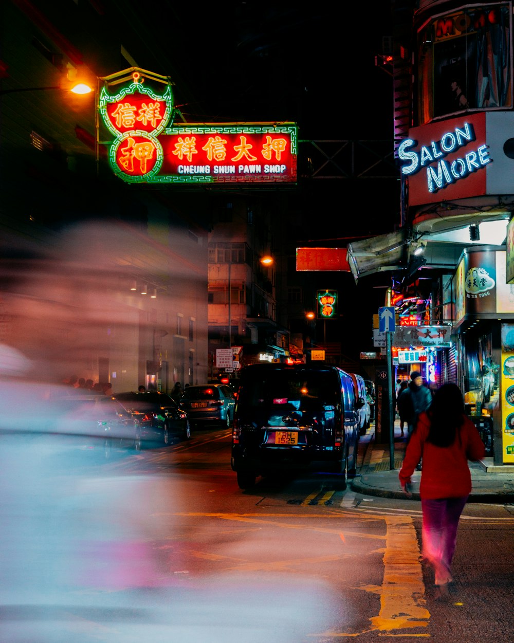 vehicles parked on sidewalk between lighted buildings at night