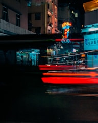 Nighttime cityscape drenched in deep shadows and neon signs flickering.