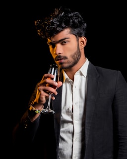 Sophisticated man in a black suit holding a glass of champagne in a glamorous gold and black casino setting.