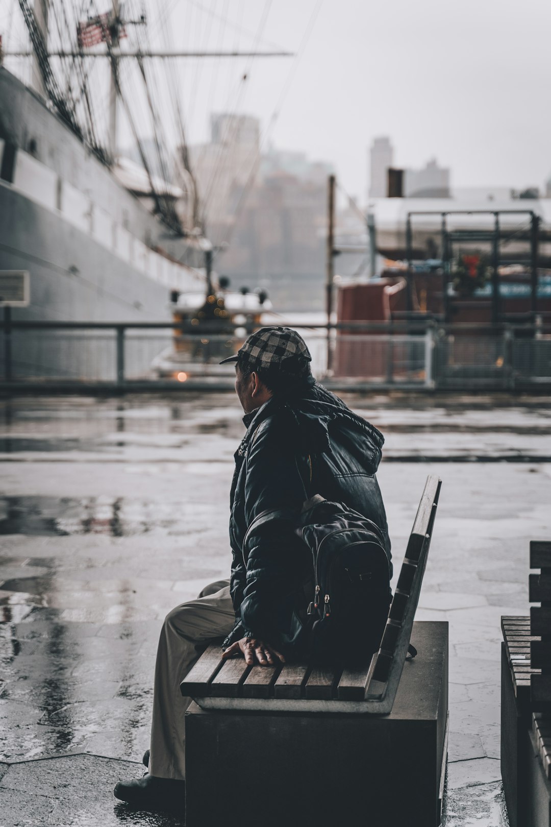man sitting on bench at the pier near ship