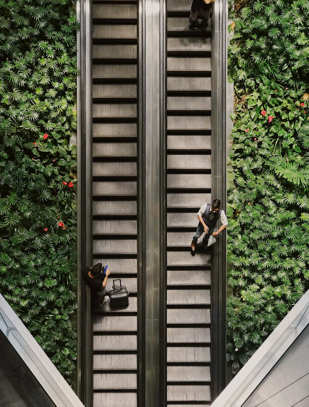 three persons standing on escalators
