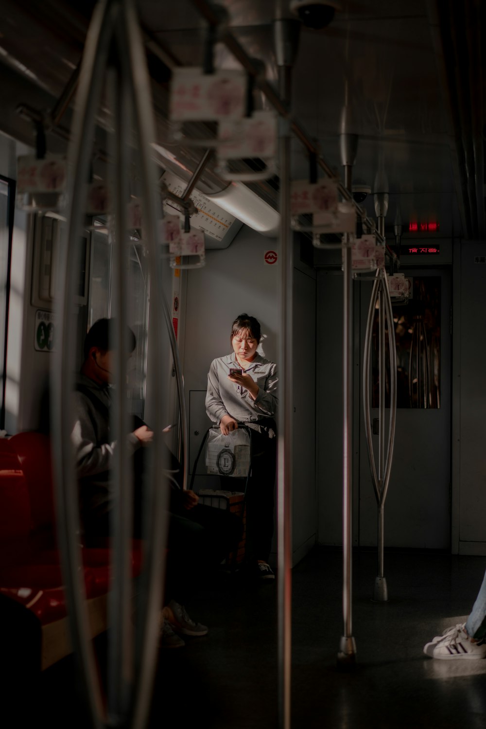 woman standing inside train using smartphone