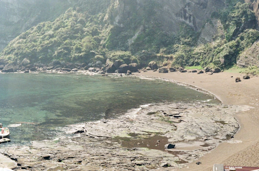 A serene hidden beach with crystal-clear turquoise water and lush greenery surrounding it.