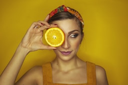 woman covering her right eye with orange slice