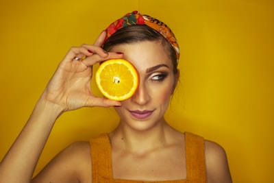woman holding orange slice to face