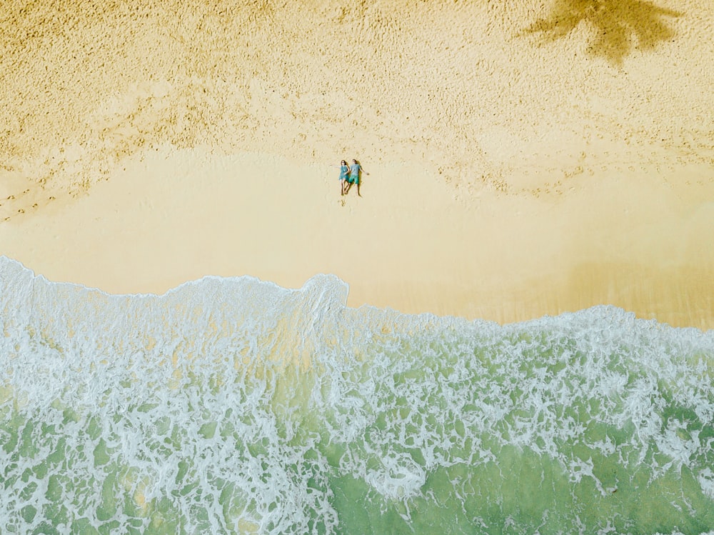 two people lying on sand seashore during day