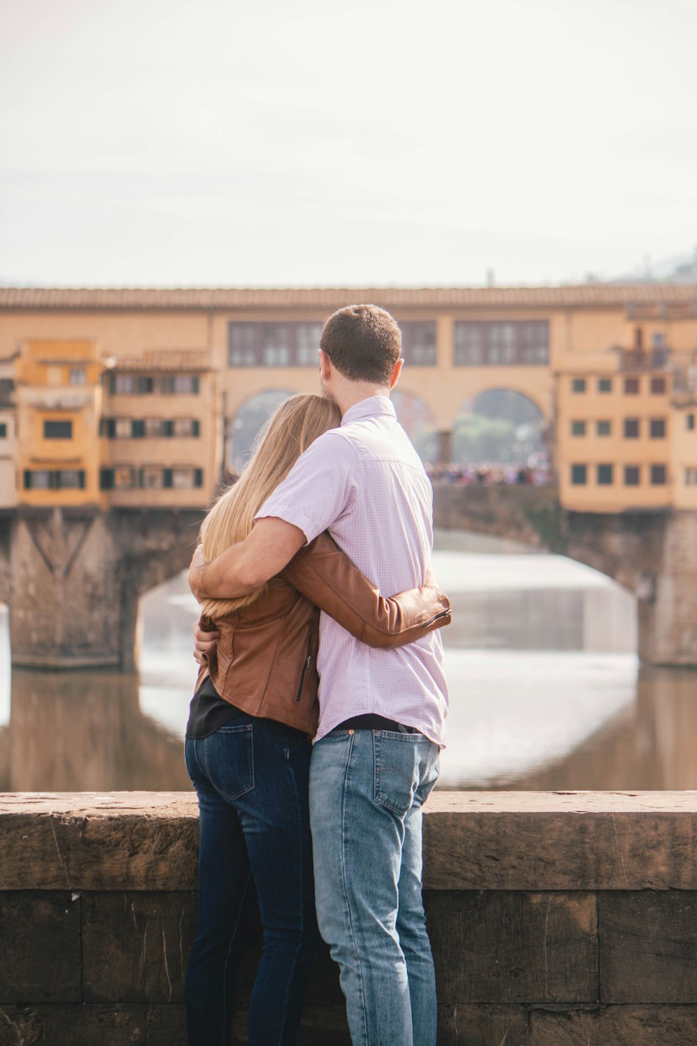 man and woman standing and hugging near body of water