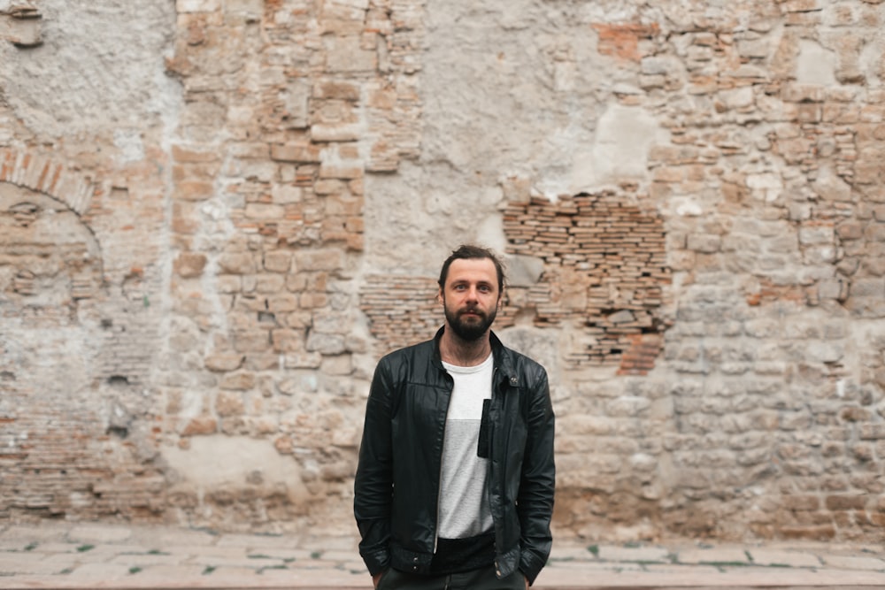 man looking at the camera in front of brick wall