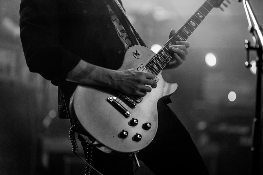 grayscale photography of man playing an electric guitar