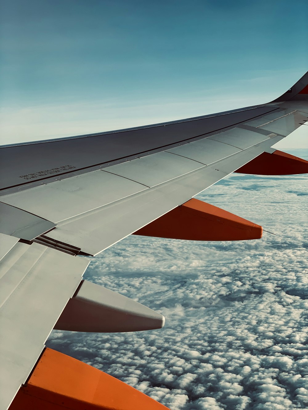 white and orange tail of airplane under blue and white sky