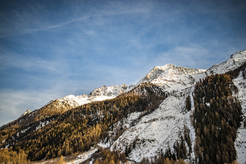 aerial photography of summit view of mountain covered with snow under blue and white sky