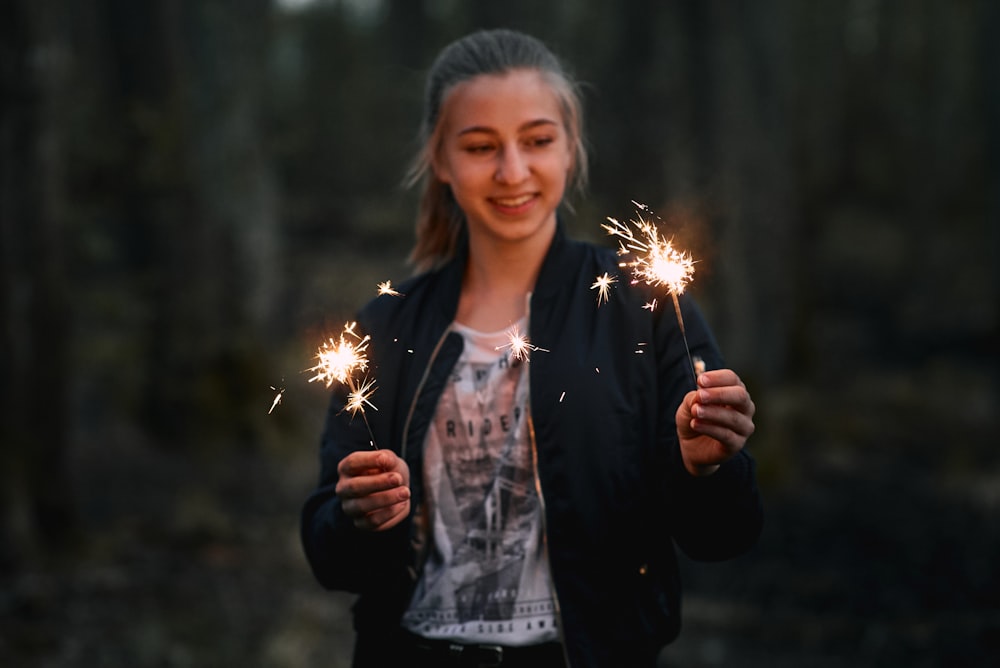 woman holding two lighted sparklers