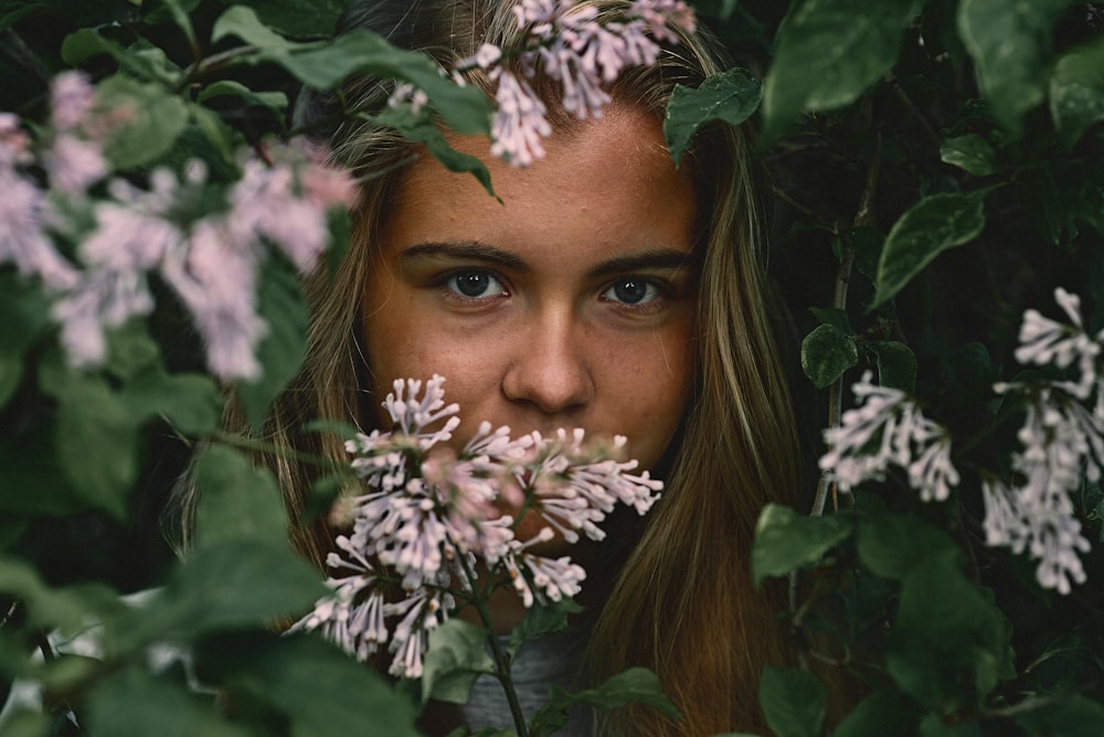 portrait photography of woman surrounded with purple-petaled flowering plant