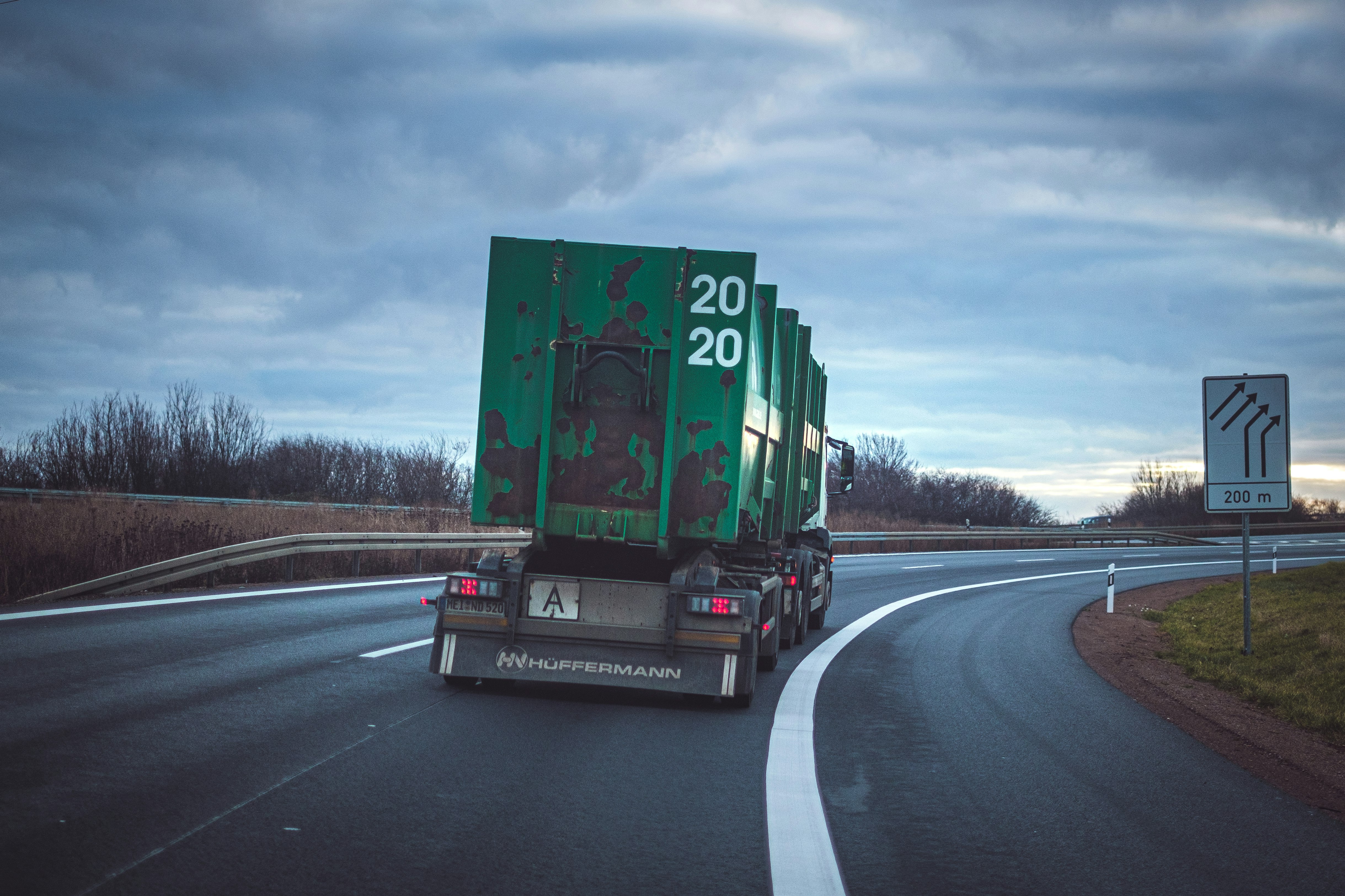 green freight truck passing by a winding road