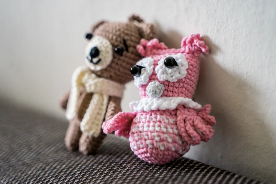 Two hand-crocheted amigurumi toys, a bear and a pink owl, side by side