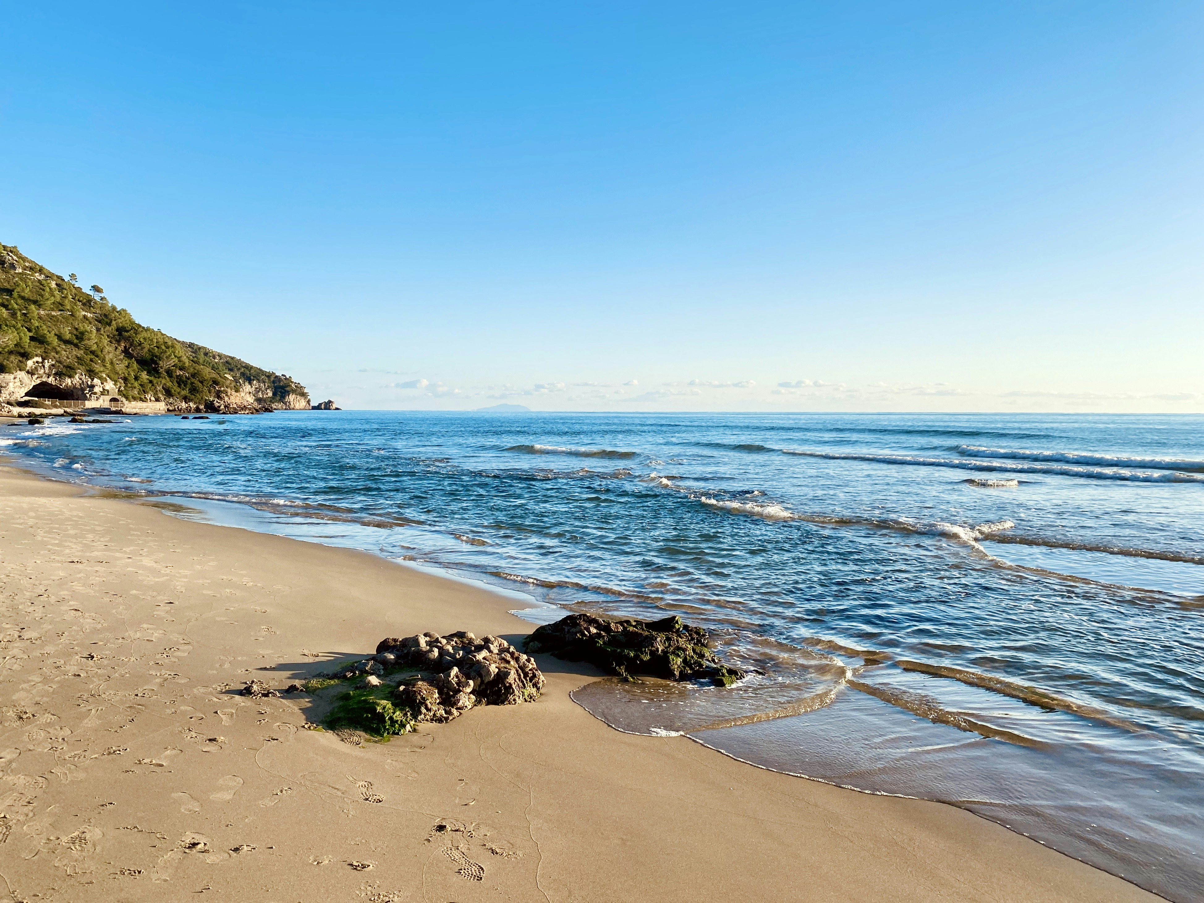 gray rocks near seashore viewing cliff under blue and white sky, Italian landscape at the end of December