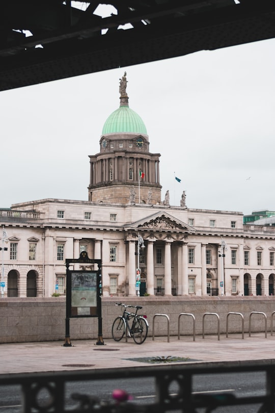 biked parked on bike rack near buildings during day in Custom House Ireland