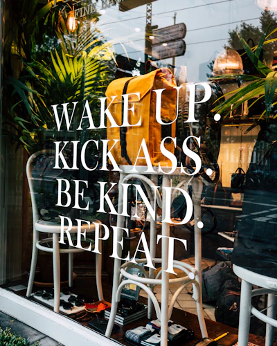 A window reading “Wake up, kick ass, be kind, repeat”