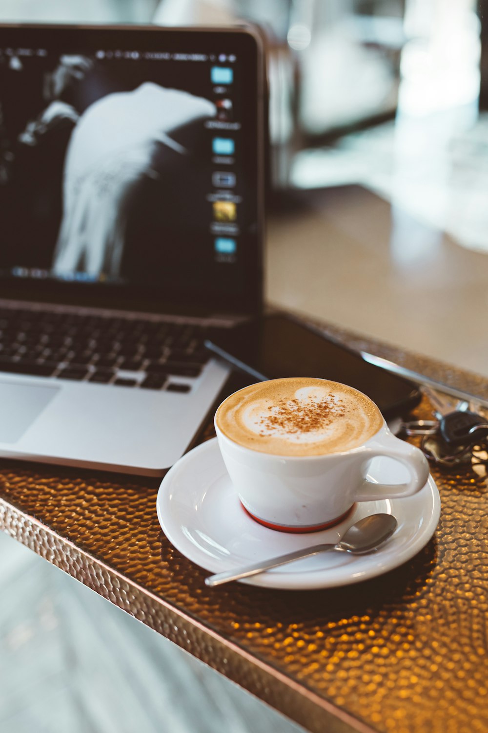 white ceramic teacup beside the laptop