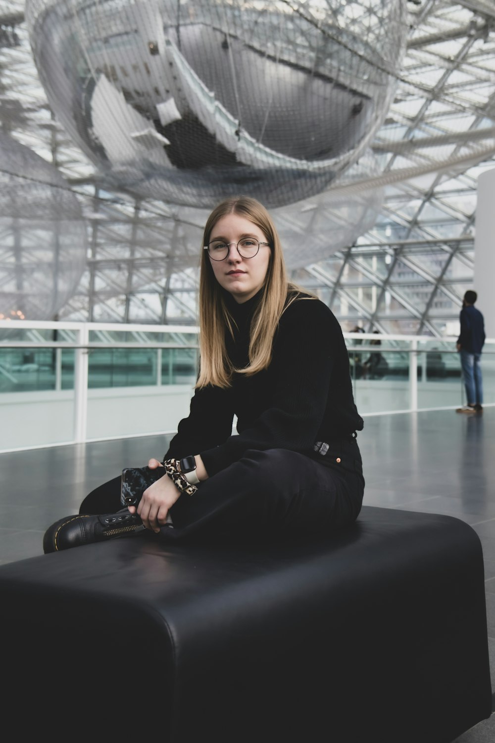 selective focus photography of woman sitting on black leather bench