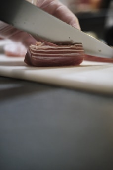 Close-up of a chef expertly slicing traditional serrano ham on a wooden stand.