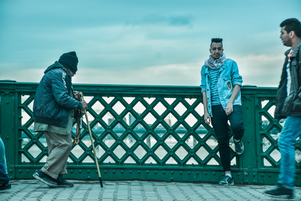 person walking with stick near two men