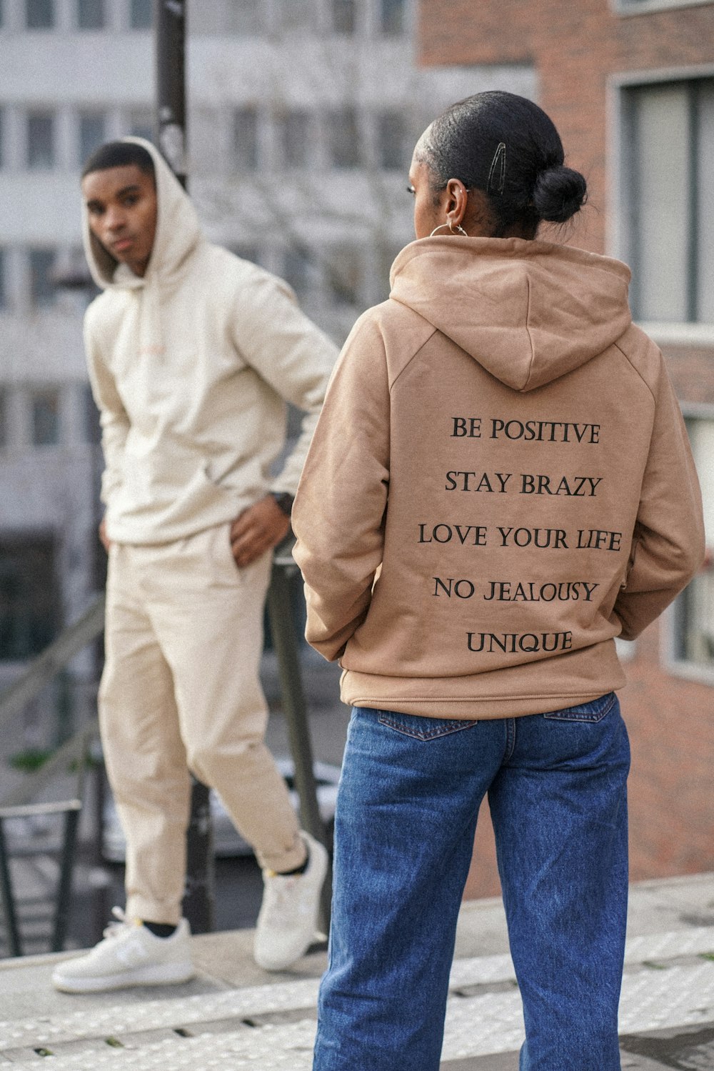 selective focus photography of woman in brown hoodie in front of man in white hoodie