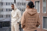 Group of friends wearing uniquely designed hoodies in an outdoor urban setting.