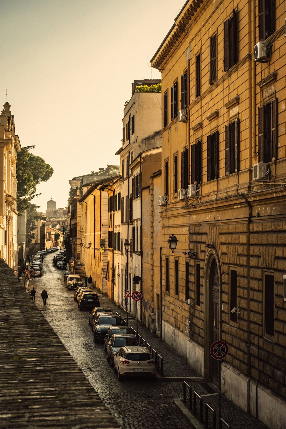 Una strada fiancheggiata da auto parcheggiate accanto a edifici alti