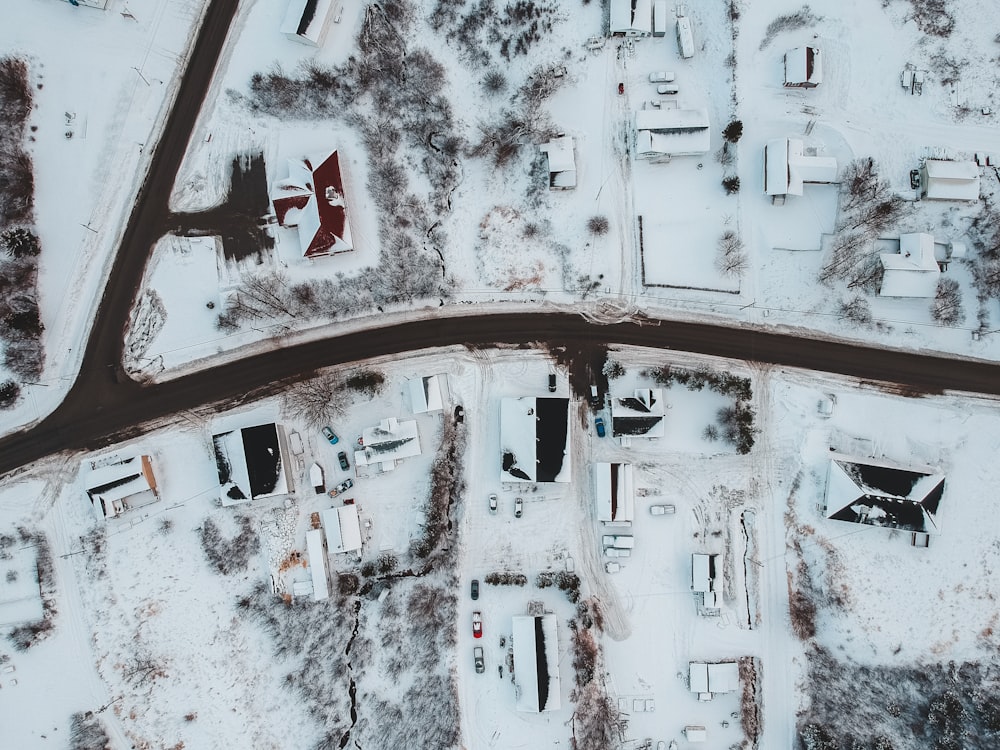 Fotografia aerea di case, campi e alberi coperti di neve durante il giorno