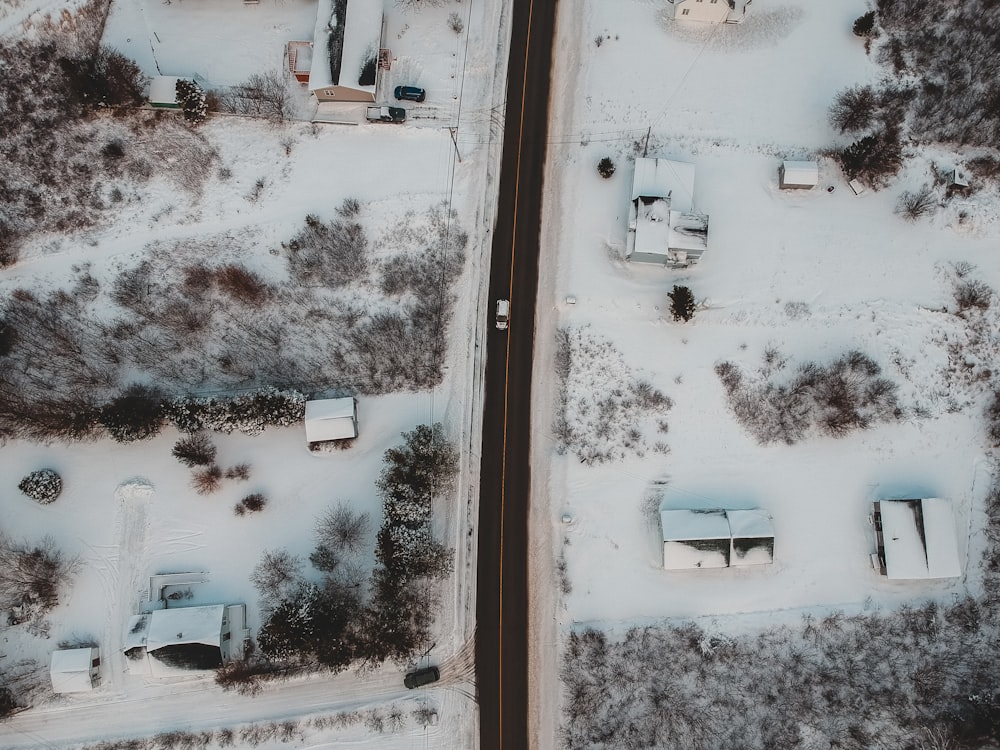 fotografia aérea de casas, campos e árvores cobertas de neve durante o dia