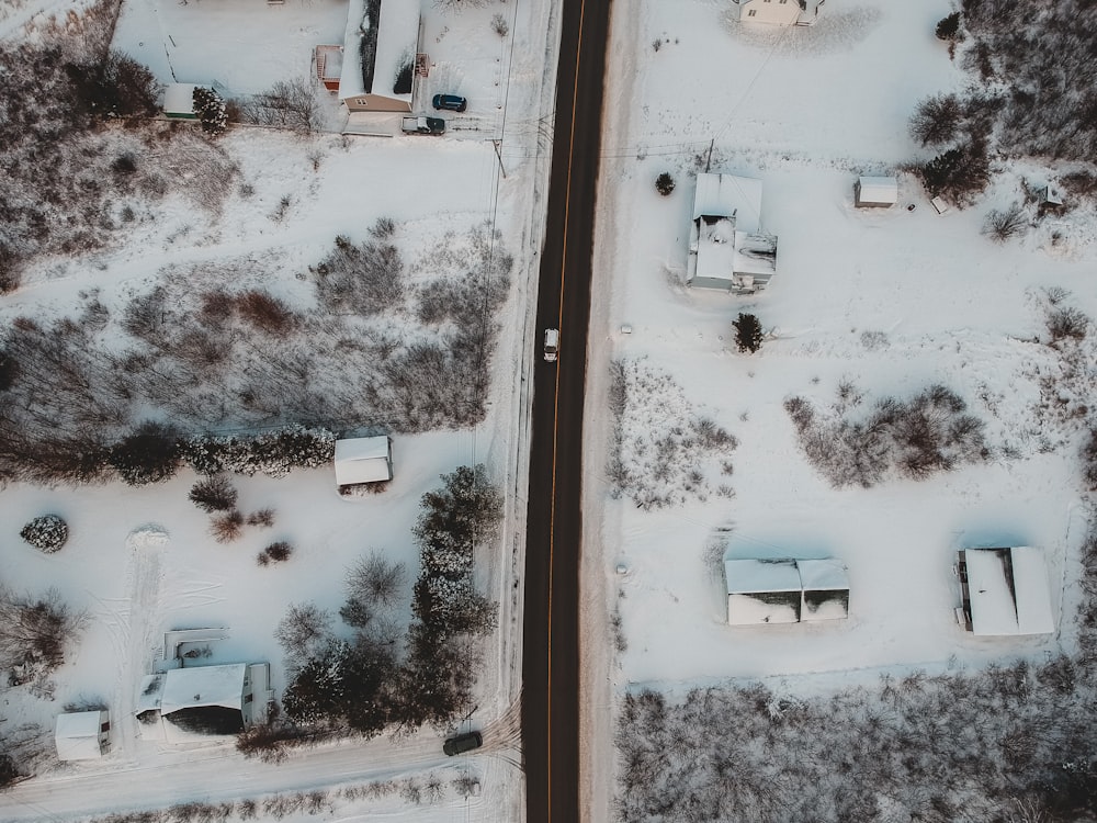 aerial photography of houses, field, and trees covered with snow during daytime