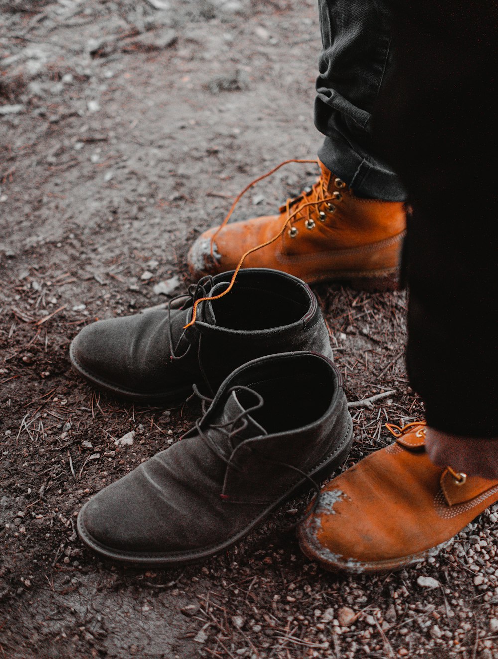 par de botas de couro preto perto da pessoa em pé