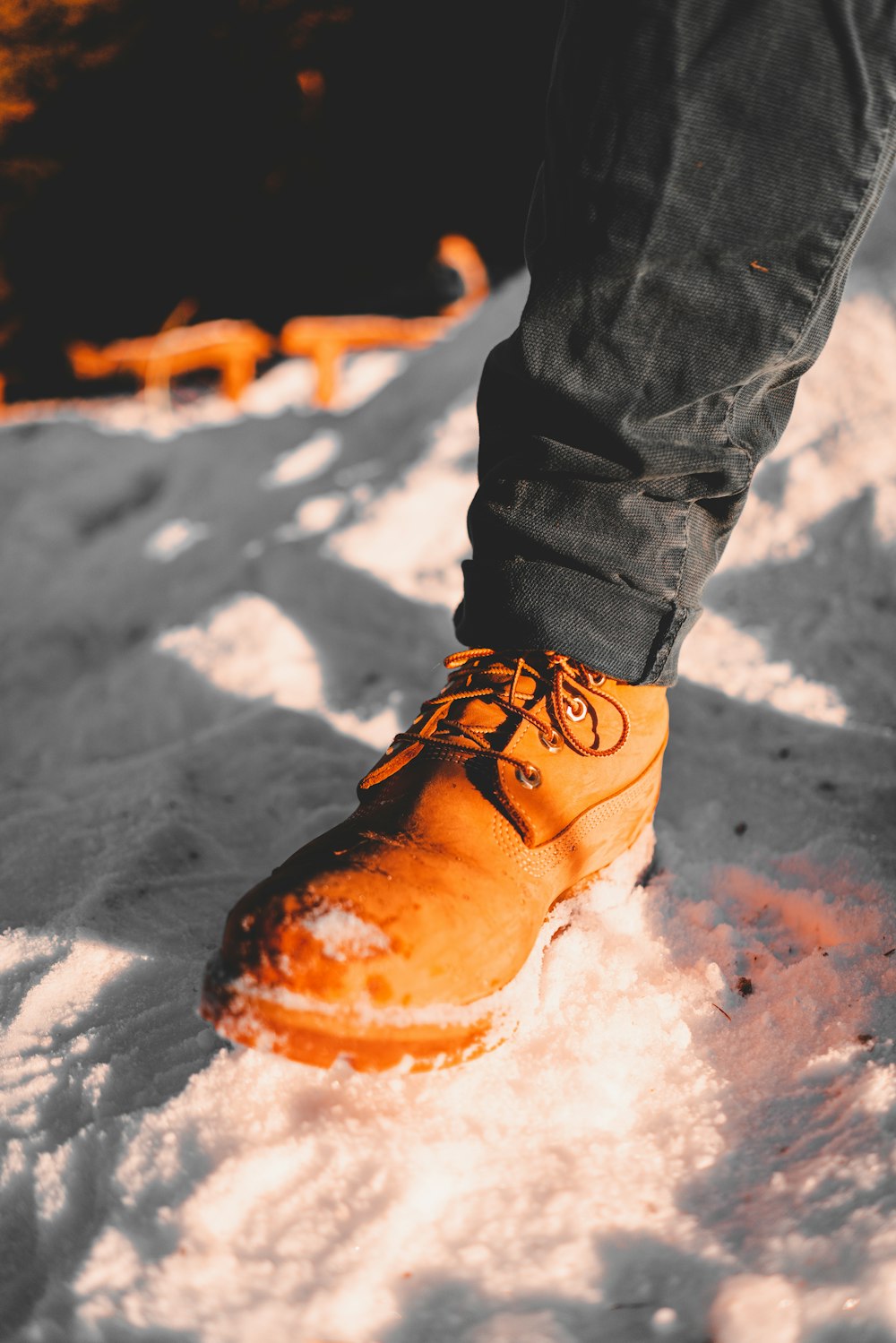 uma pessoa em pé na neve usando um par de sapatos laranjas