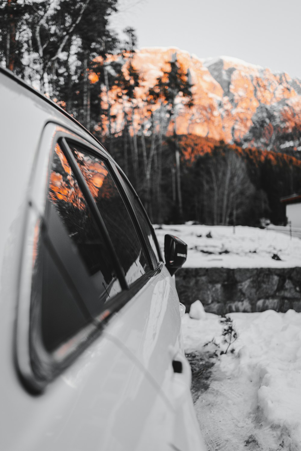 昼間の雪原展望崖に白い車を駐車