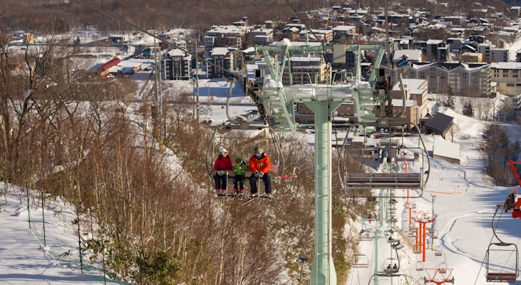 Skiers riding a chairlift above a snow-covered Japanese resort