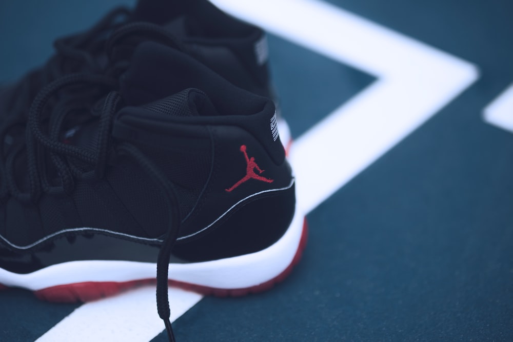 schwarze, weiße und rote Air Jordan 11 auf grauem Untergrund