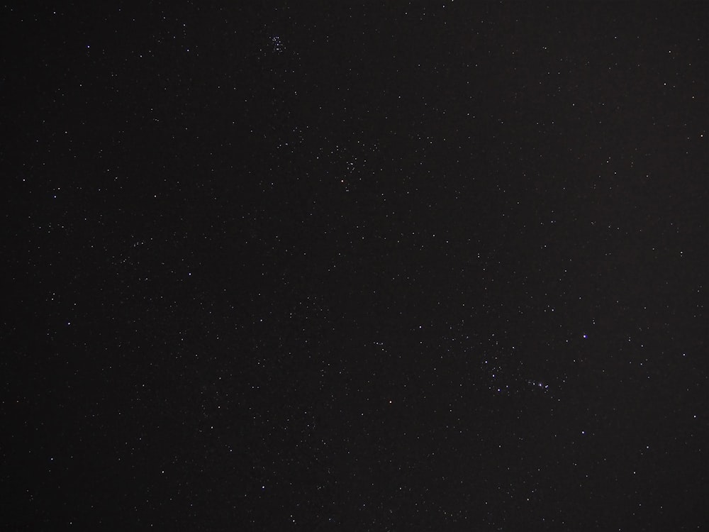 a night sky with stars and a plane in the foreground