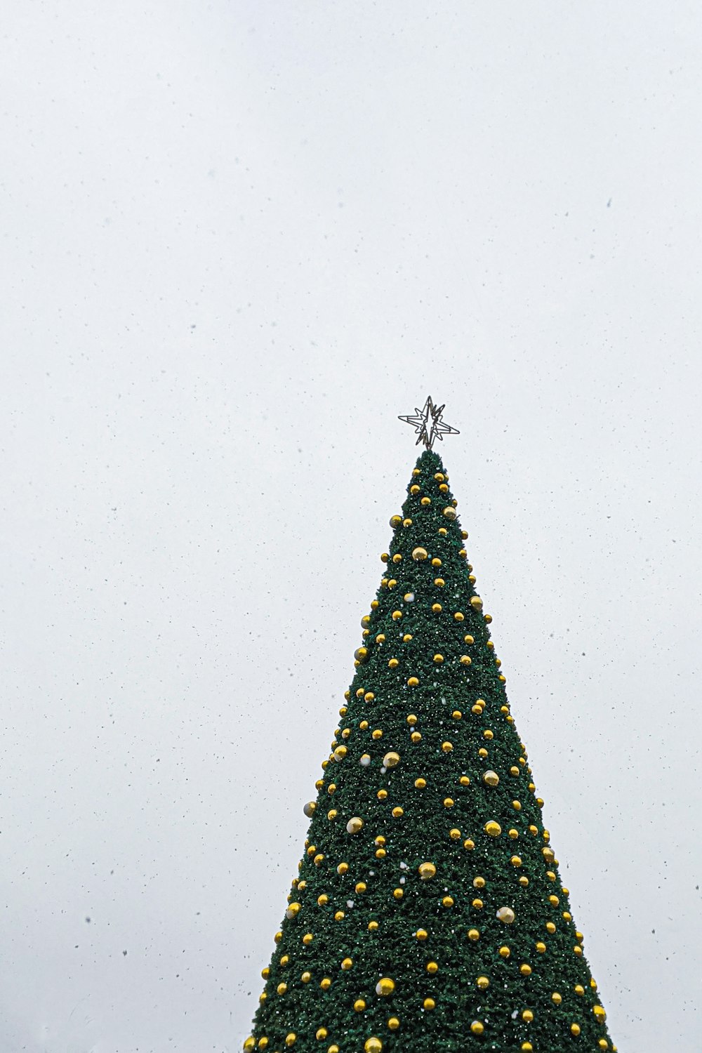 黄色の安物と銀色の星のトッパーと緑のクリスマスツリーの低角度写真