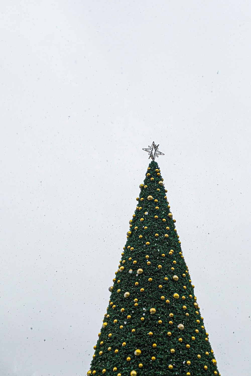 노란색 값싼 물건과 은색 별 토퍼가 있는 녹색 크리스마스 트리의 로우 앵글 사진