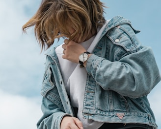 woman wearing white crew-neck t-shirt and blue denim jacket standing while looking down