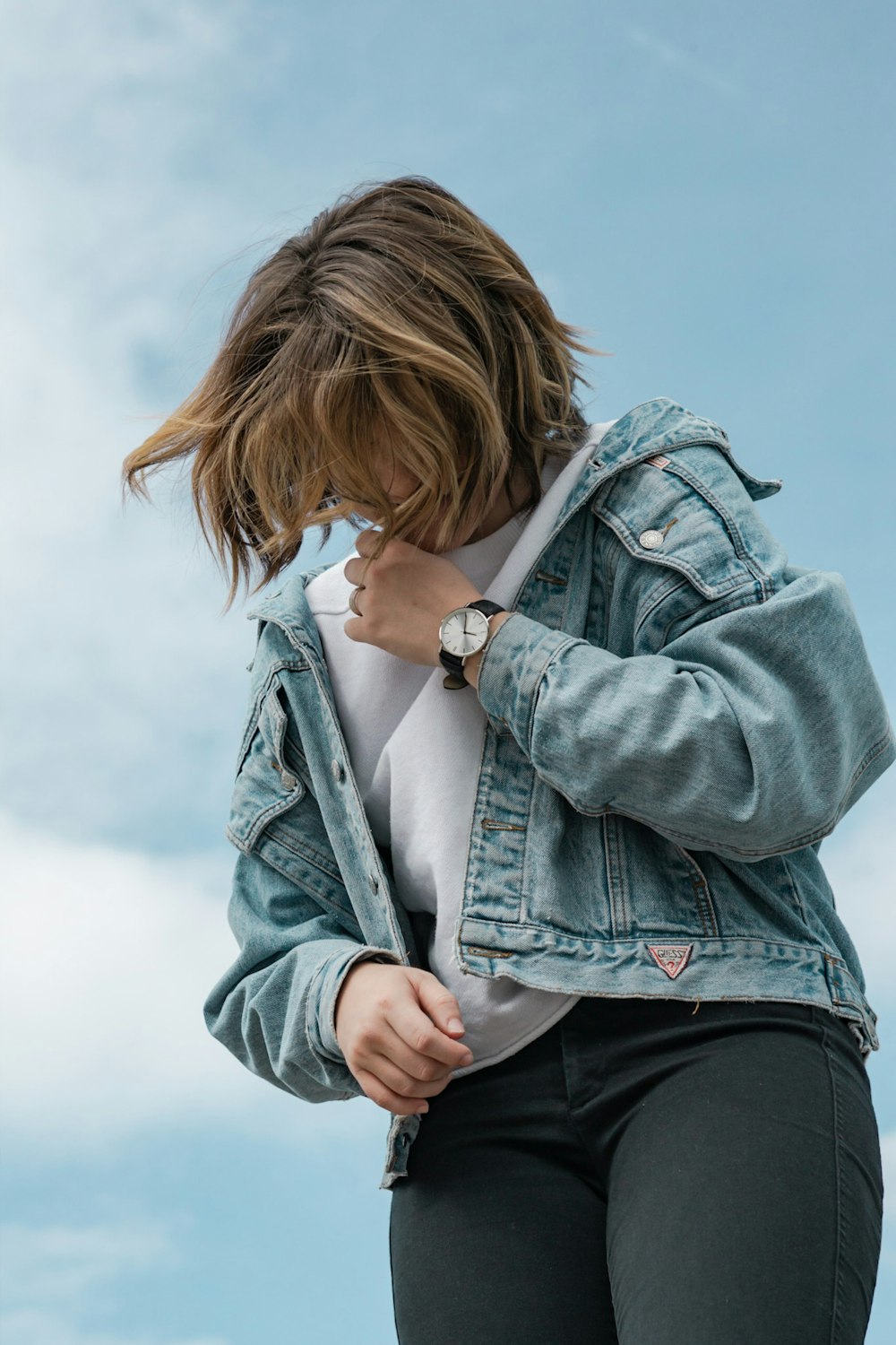 woman wearing white crew-neck t-shirt and blue denim jacket standing while looking down