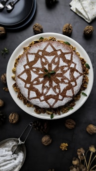 A bespoke designer cake featuring geometric patterns inspired by traditional Arab art, displayed on a rustic wooden table.