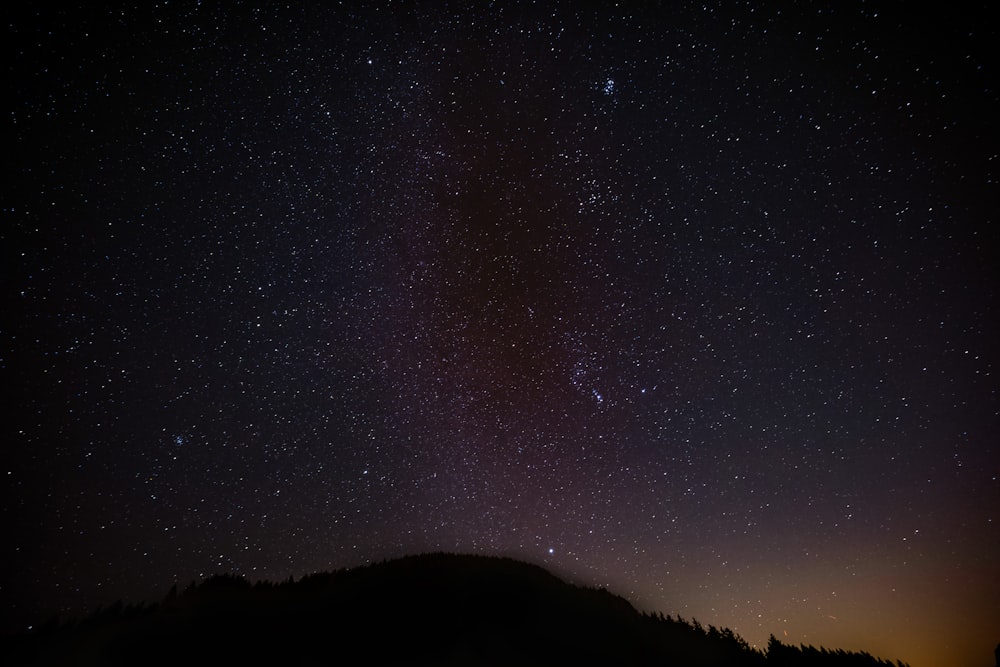 the night sky with stars above a mountain